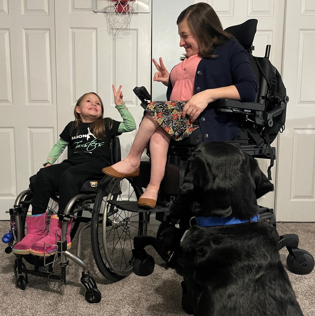 Kara sits in her Stretto Power Wheelchair, elevated at iLevel