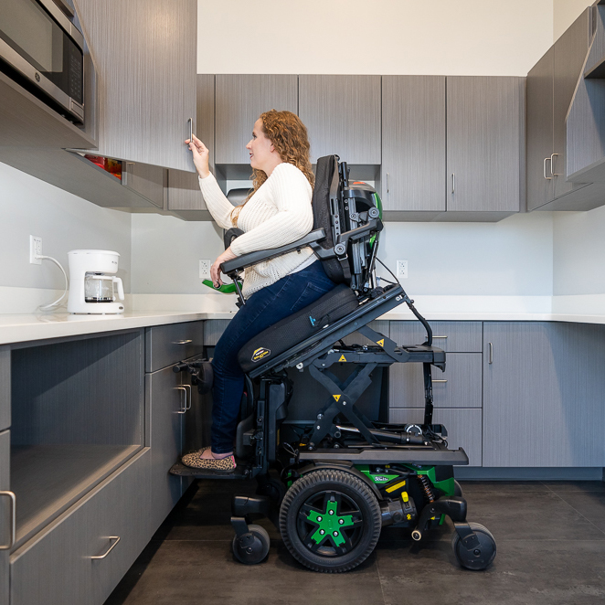 A consumer uses anterior tilt on her Quantum power wheelchair for reaching