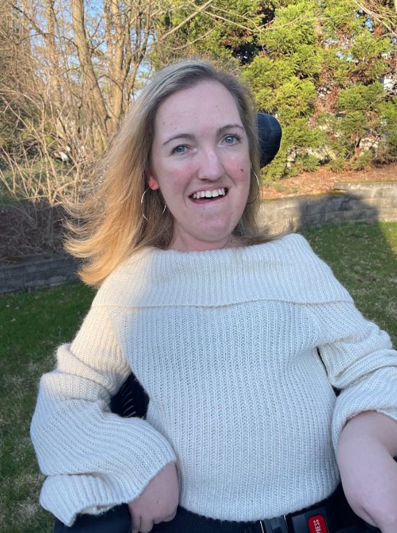 Image of Marianne the author wearing a white sweater outside smiling